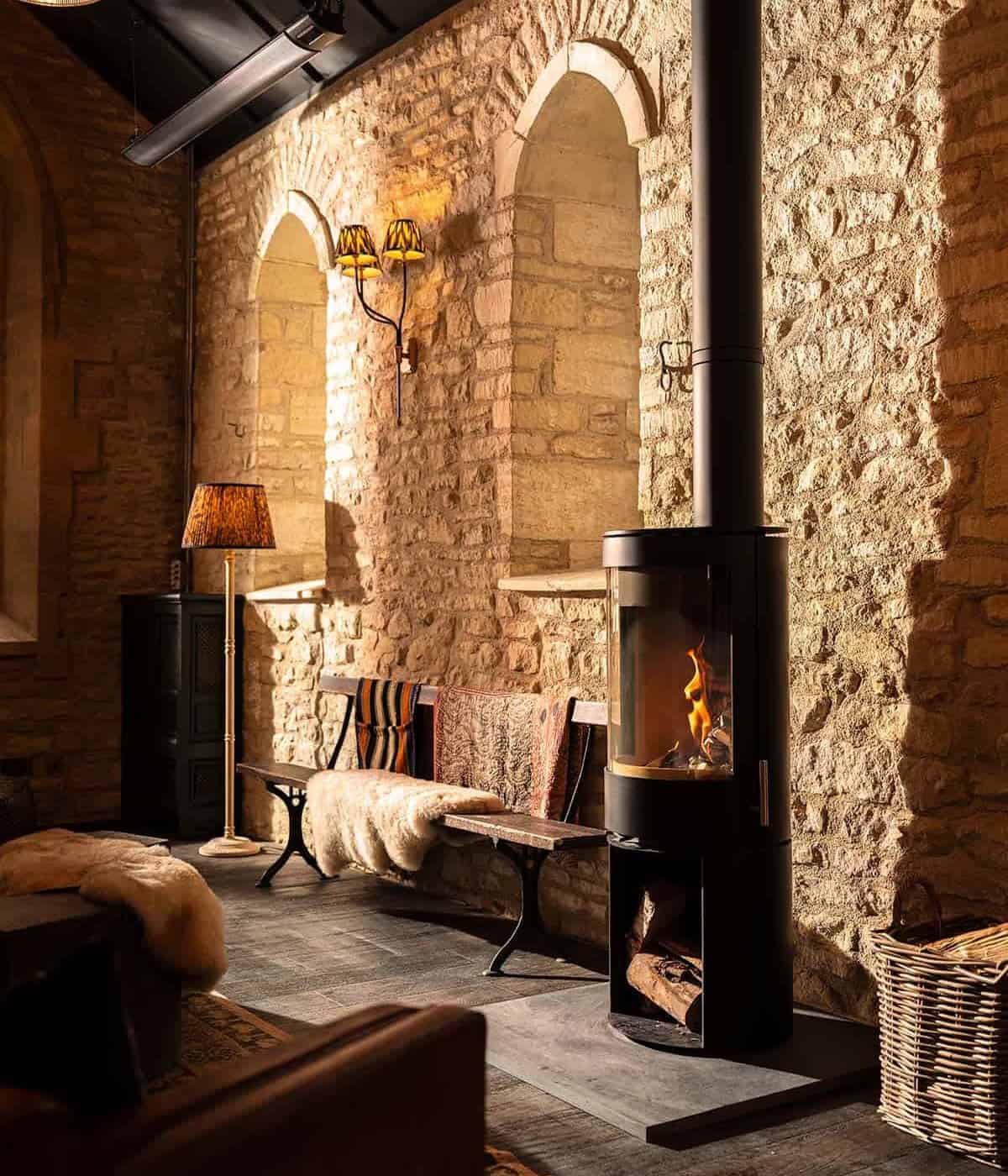 Warm living space featuring a sleek black wood stove against exposed brickwork.