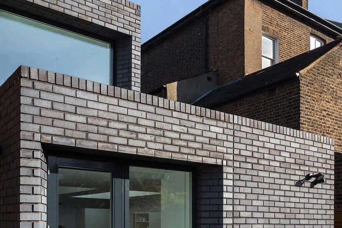 Bright and modern Victorian-inspired brick extension with large glass doors.